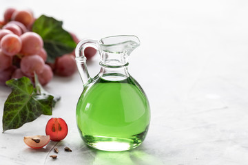 Grape seed oil in a glass bottle with a bunch of grapes on a white background. copy space.