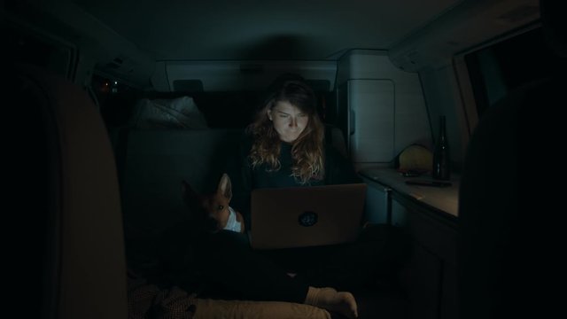 Woman with laptop inside camping van at night