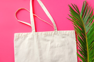 Blank white mockup linen cotton shopper tote bag green palm leaf on fuchsia pink background. Zero...