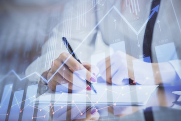 Double exposure of hands making notes with forex chart huds. Stock market concept.