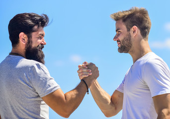 Handshake arm wrestling style. Strong and muscular arms. Successful deal handshake blue sky...