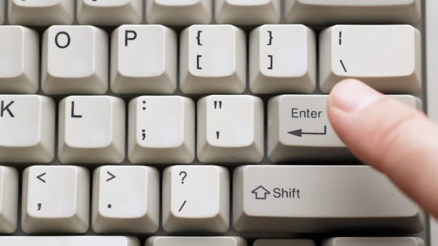 Male finger pushes ENTER button on white keyboard. Slow motion and macro view
