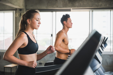 Fototapeta na wymiar Young couple Exercising by running on the treadmill To maintain good health always