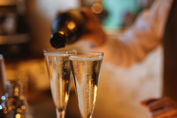 Bartender filling a flute glass with sparkling wine. Lifestyle selective focus horizontal photo