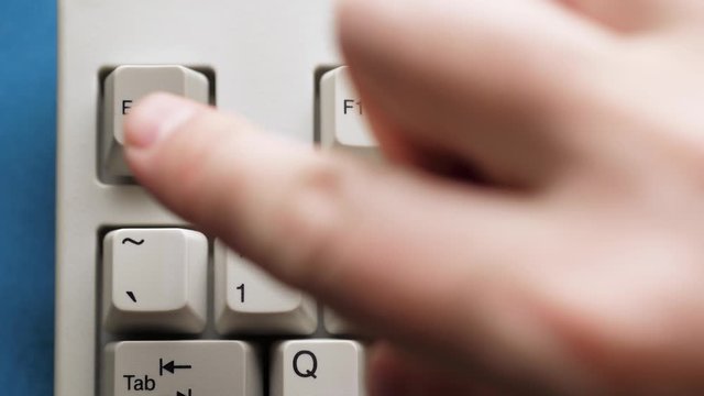 Male finger pushes ESC button on white keyboard. Slow motion and macro view