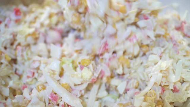 Close up woman making a healthy salad. Woman mixes mayonnaise in onion and cabbage salad of corn and crab meat.