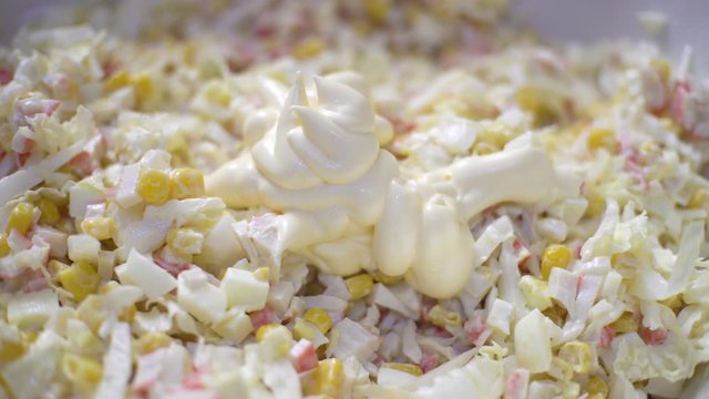 Close up woman making a healthy salad. Woman mixes mayonnaise in onion and cabbage salad of corn and crab meat.