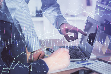 Double exposure of graph with man typing on computer in office on background. Concept of hard work. Closeup.