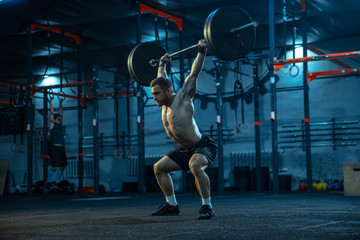 Caucasian man practicing in weightlifting in gym. Caucasian male sportive model training with barbell, looks confident and strong. Body building, healthy lifestyle, movement, activity, action concept.