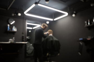 Blurred photo of a barber shop room in black style and lamps.