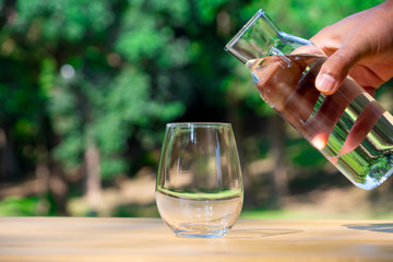 Prepare to pouring pure water in to the glass with background nature