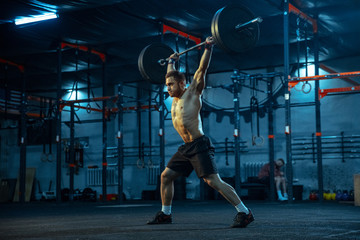 Caucasian man practicing in weightlifting in gym. Caucasian male sportive model training with barbell, looks confident and strong. Body building, healthy lifestyle, movement, activity, action concept.