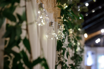 close up photo of a hanging row of light bulbs on the wall in a banquet hall