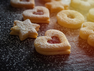 Homemade Linzer Christmas cookies. Biscuits with shortcrust pastry and strawberry jam on dark background.