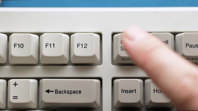 Male finger pushes PRINT SCREEN button on white keyboard. Slow motion and macro view