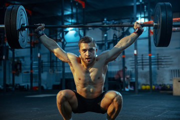 Caucasian man practicing in weightlifting in gym. Caucasian male sportive model training with...