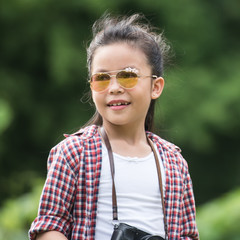 Happy asian kid girls to summer travel trip with green background. She traveled alone with checks map to find directions. Travel and adventure concept.