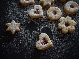 Homemade Linzer Christmas cookies. Biscuits with shortcrust pastry and strawberry jam on dark background.