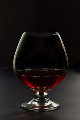 Cognac in a glass, in a dark vein, in backlight