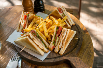 Fresh club sandwich with ham, cheese and potatoes on wooden background