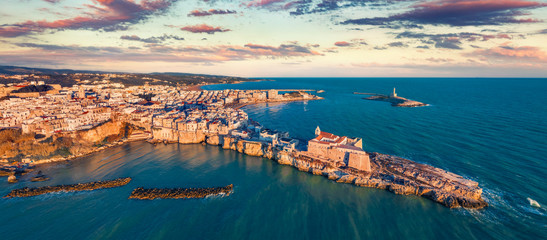Panoramic view from flying drone. Amazing morning cityscape of Vieste - coastal town in Gargano National Park with Castello Svevo, Italy, Europe. Bright spring sunrise on Adriatic sea.