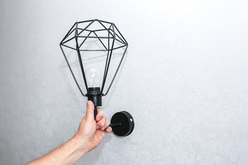 Man holding lamp in hands. Electricity installation. Modern loft design. Restoration indoors. Maintenance work.