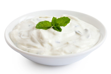 Tzatziki in white ceramic bowl isolated on white. Mint leaf garnish.