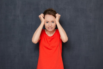 Portrait of disappointed young woman raising clenched fists to head