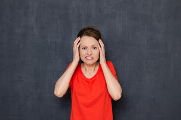 Portrait of frightened young woman raising hands to head