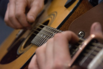 Fototapeta premium Guitar deck and guitarist hands closeup. Capo on the fretboard of a guitar. Blurred guitar background