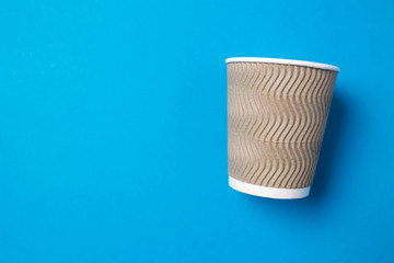 Paper cup for hot coffee or tea on a blue isolated background.
