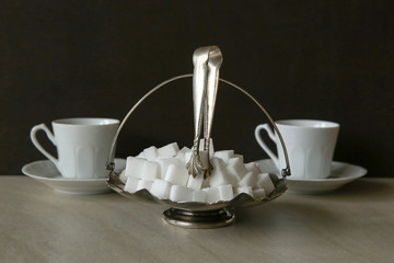 Sugar cubes in metal vintage sugar  bowl with sugar tongs..
