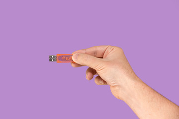 Orange USB flash memory on hand with isolated violet background