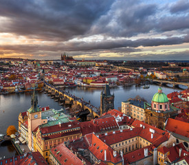 Prague, Czech Republic - Aerial panoramic drone view of the world famous Charles Bridge (Karluv most) and St. Francis Of Assisi Church with a beautiful winter sunset. St. Vitus Cathedral at background