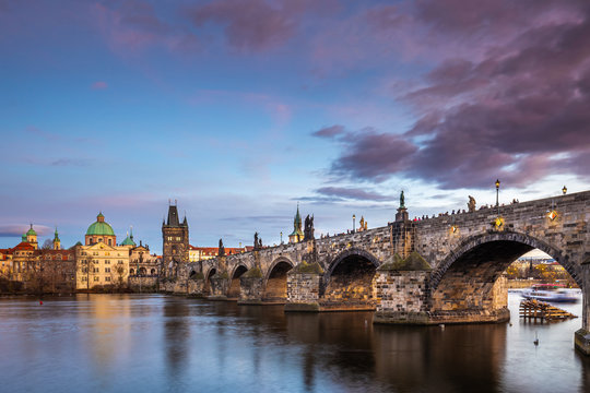 Prague, Czech Republic - Beautiful purple sunset and sky at the world famous Charles Bridge (Karluv most) and St. Francis Of Assisi Church on a winter afternoon