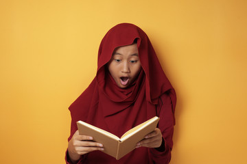 Asian Muslim Teenage Girl Wearing Hijab Shocked and Excited When Reading Book