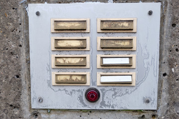 Old and weathered metal doorbell panel  with unreadable names with a red light switch on a frosty morning in winter. Seen in January in Bavaria, Germany