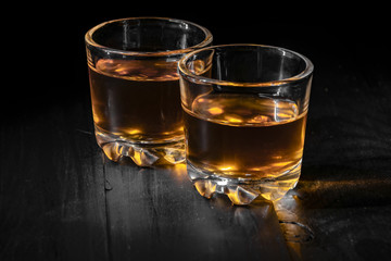 two glasses of cognac on a black tree