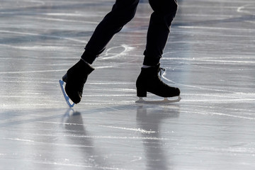 Fototapeta premium Legs of a man skating on an ice rink. Hobbies and sports. Vacations and winter activities.
