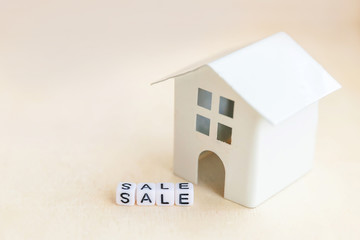 Miniature toy model house with inscription SALE letters word on wooden backdrop. Eco Village abstract environmental background. Real estate mortgage property insurance sweet home ecology rent concept
