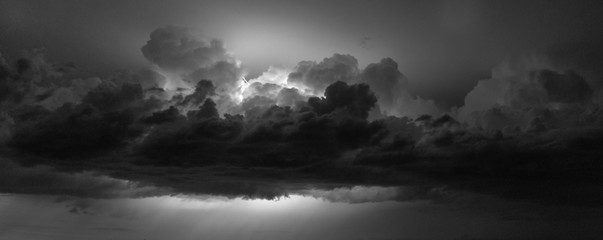 Black and white panorama of lightning flashing between the clouds of a Great Plains thunderstorm