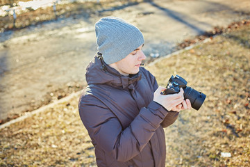 photographer in a hat, makes a photo on his camera in the winter park