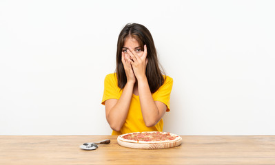 Caucasian girl with a pizza covering eyes and looking through fingers