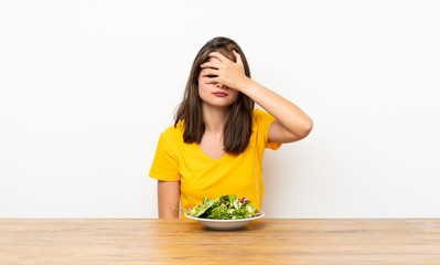 Caucasian girl with salad covering eyes by hands