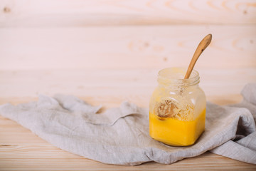 A jar of solid honey and cloth on wooden background.