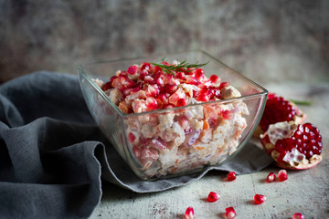 Spicy salad with meat and pomegranate seeds dressed with mayonnaise on a gray napkin
