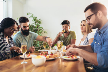 Enjoying dinner with friends. Group of cheerful young people enjoying dinner.