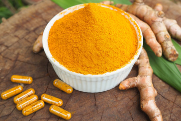 Turmeric powder and fresh turmeric in white bowl on vintage old wooden table. herbal