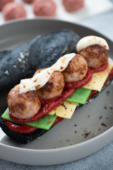 Close-up of submarine sandwich with black baguette, meatballs and cheese, selective focus, vertical shot