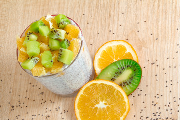 healthy breakfast of chia seeds of orange and kiwi yogurt on a wooden background fitness food. copy space